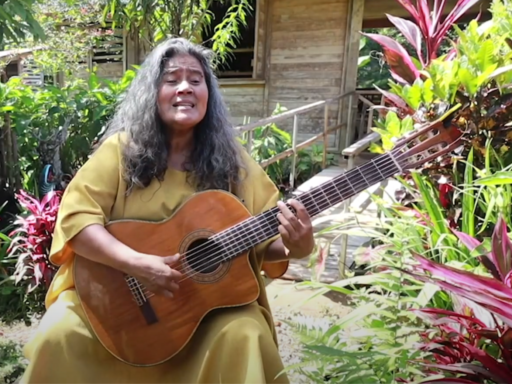 Eine Frau spielt Gitarre und singt im Regenwald